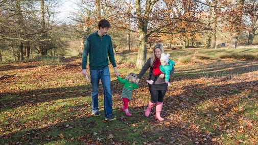 A family of four enjoying a walk through a wooded area on the parkland at Knole in kent